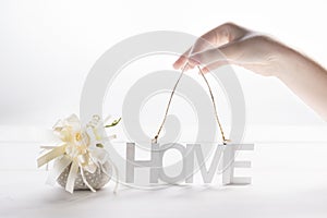 Nordic style still life - Female hands hold inscription Home on a white background, backlight, the concept of home or home