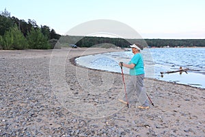 Nordic Walking - elderly woman is hiking along the river