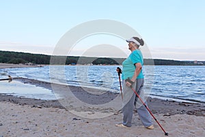 Nordic Walking - elderly woman is hiking along the river