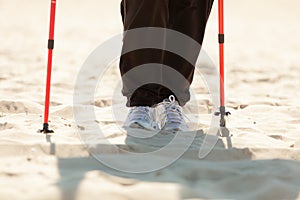 Nordic walking. Female legs hiking on the beach.