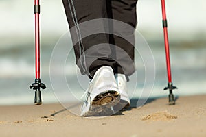 Nordic walking. Female legs hiking on the beach.