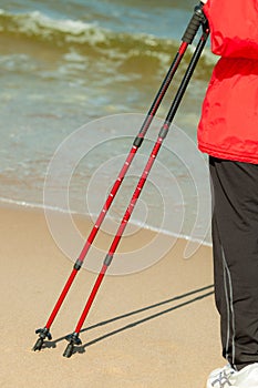 Nordic walking. Female legs hiking on the beach.