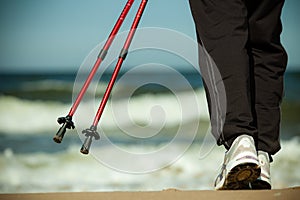 Nordic walking. Female legs hiking on the beach.