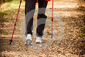 Nordic walking. Female legs hiking in forest or park.