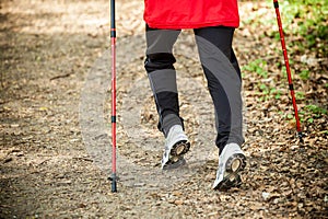 Nordic walking. Female legs hiking in forest or park.