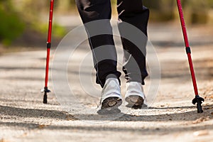 Nordic walking. Female legs hiking in the park.