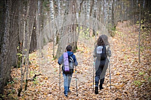 Nordic walking. Little boy and young woman. Back view. Fall season