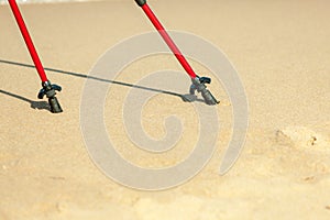 Nordic walking. Red sticks on the sandy beach