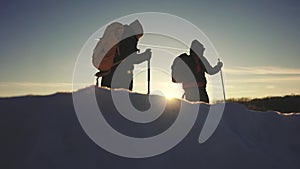 nordic walking in winter. winter hike group of tourists silhouette. teamwork travel. sunset two hikers with sticks walk