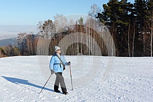 Nordic Walking - woman in a blue jacket hiking on snow