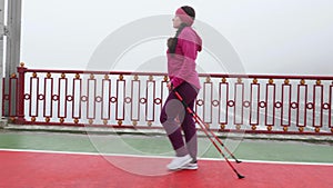 Nordic walking. Young chubby Caucasian woman hiking with the Nordic poles. Side Follow Shot