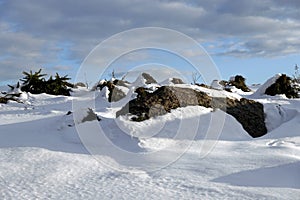 Nordic winter landscape with hills and big stones on clean sparkling snowy surface on sunny bright day