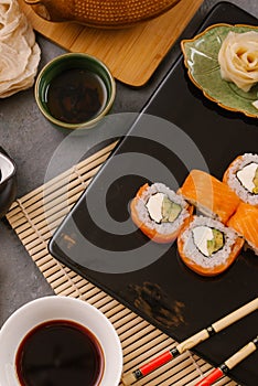 Nori Maki Philadelphia Sushi Rolls Set with Raw Salmon and Cream Cheese on Black Stone Table Background with Place for Text.