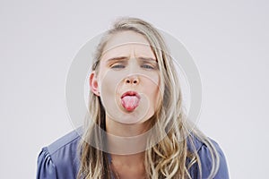 Normal is for boring people. Studio shot of a young woman making a funny face against a gray background.