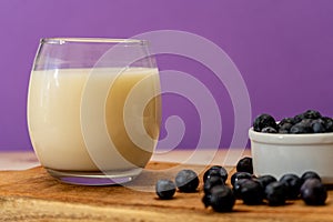 Normal view of a glass of milk next to some blueberries in a modern, stripped-down setting. Healthy eating photo