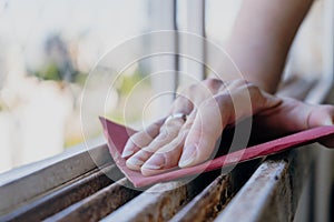 Normal view of a woman`s hands sanding a window frame before painting. Empowered woman concept