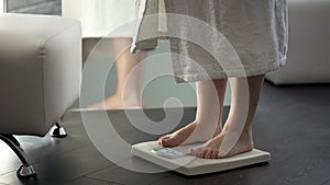 Normal weight, girl checking dieting results on scales at home, healthy body