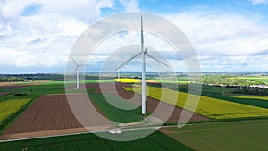 Norman wind turbines in the middle of the countryside and fields of rapeseed and barley