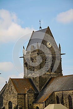 Normandy, France; 4 June 2014: Airborne paratrooper gets stuck on a church in Saint Mere Eglise in Normandy during World War II