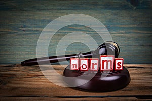 NORMS. Red alphabet letters and judge's gavel on wooden background. Laws and justice concept photo