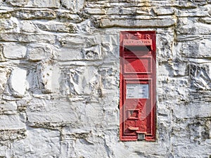 NORTH DEVON, MARCH 13 2022: Bright red Victorian Post Office post box in old wall. Devon, UK.