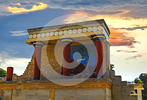 North Entrance of the Knossos Palace complex with charging bull fresco and red columns, with red orange sunset clouds in