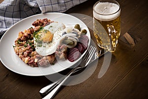 North German Hamburg Labskaus is a delicacy with corned beef, potatoes, beetroot, pickled gherkins, fried egg, herring and beer on