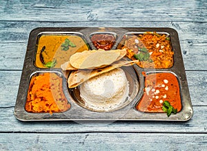 north indian vegetarian meal thali with curry, rice, chapati and vegetables served in dish isolated on wooden table top view of