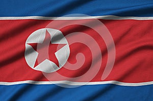 North Korea flag is depicted on a sports cloth fabric with many folds. Sport team banner