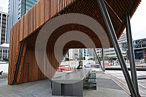 Modern wood North Kumutoto Pavilion with strips on folded plates and steel posts on plaza in Wellington CBD, New Zealand