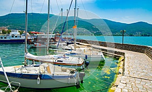 North macedonia. Ohrid. Different sail boats beside dock on ohrid lake with mountaines on background