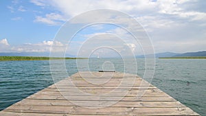 North macedonia. Ohrid. Wood pier in Ohrid lake in sunny day with reeds, pier and mountaines on background.