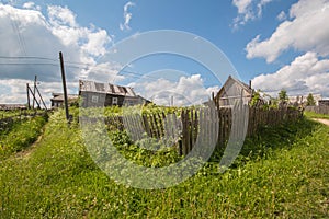 North Russian village Isady. Summer day, Emca river, old cottages on the shore, old wooden bridge. Abandoned building. photo