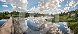 North Russian village Isady. Summer day, Emca river, old cottages on the shore, old wooden bridge and clouds reflections.