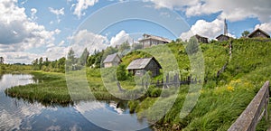 North Russian village. Summer day, river, old cottages on coast.