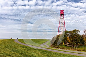 The North Sea dike and the steel lighthouse Campen with a blue cloudy sky.