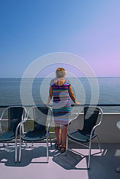 North Sea Netherlands 26-july-2018 Woman stands at the railing of a ship that sails on a calm ocean in summer time, and looks out