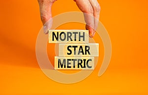 North star metric symbol. Concept words North star metric on wooden blocks on a beautiful orange table orange background.