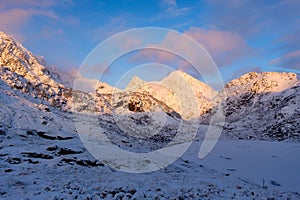 North. Winter landscape during sunset. Bright sky. Mountain peaks during sunset. Snowy winter.