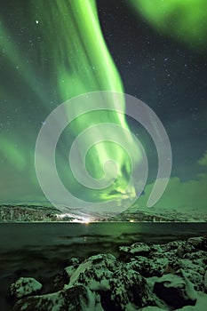 Northern lights, aurora borealis, above a fjord surrounded by a