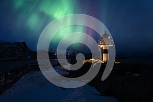 Northern lights, Aurora borealis in Lofoten islands, Norway. Night winter landscape with polar lights and lighthouse