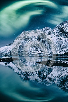 Northern lights, Aurora borealis, Lofoten islands, Norway. Night winter landscape with polar lights, starry sky and mountains