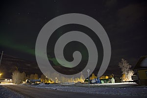 The northern lights aurora borealis rising behind a mountain in a small village in the north of Norway. In the middle of winter