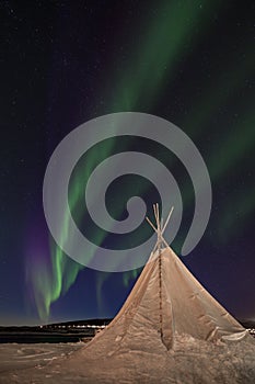 Northern Lights dancing over a traditional sami tent