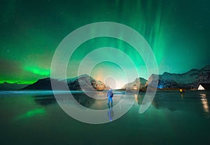 Northern Lights and man on the beach at night. Aurora borealis