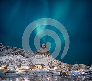 Northern lights on snow mountain with fishing village at Lofoten islands