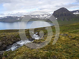 Northern summer landscape, beautiful snow covered cliffs and Alfsfell mountain, sea in Hloduvik cove with wild water photo