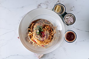 Northern Thai khao soi chicken curry noodles in a dish isolated on mat top view on grey marble background