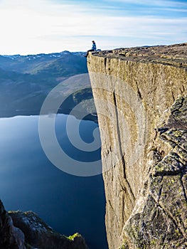 Norway - Boy sitting on a steep cliff with the view on Lysefjorden