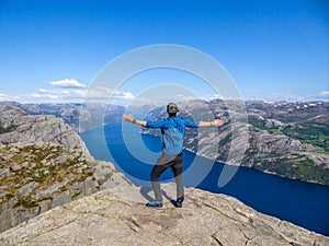 Norway - Boy standing on a steep cliff with the view on Lysefjorden